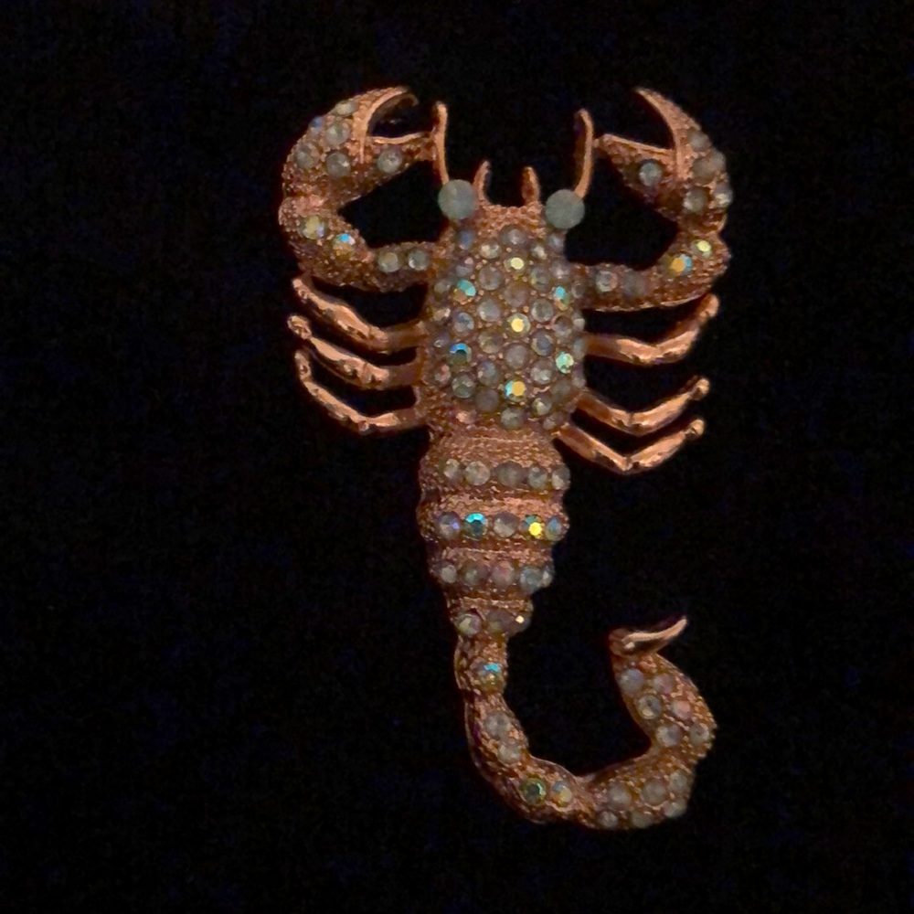 Gold scorpion pin with blue stones.